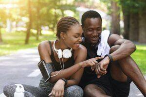 Black Couple Using Smartwatch Fitness Tracker After Outdoor Workout, Checking Burned Calories